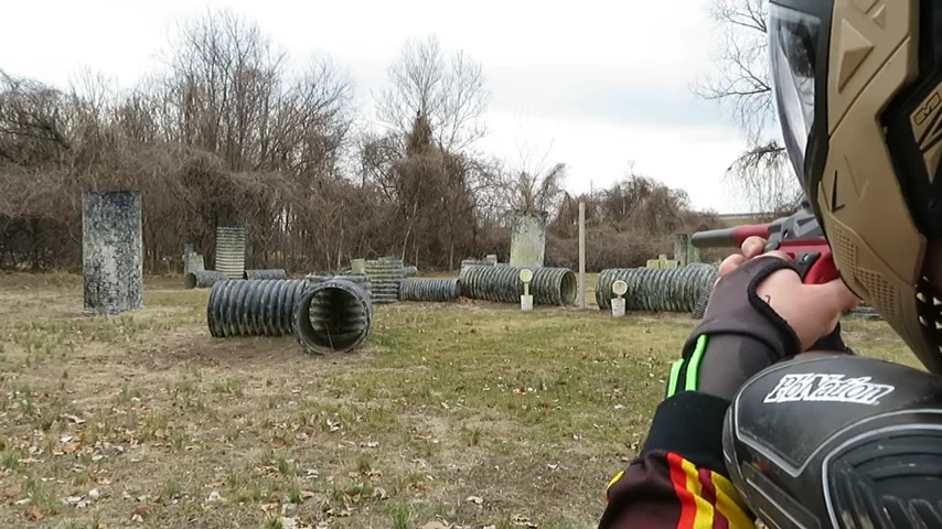 A player aiming a paintball marker with both eyes open
