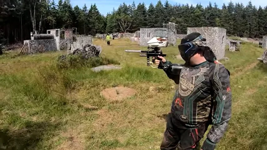 A paintball player using cover and moving with purpose on the field