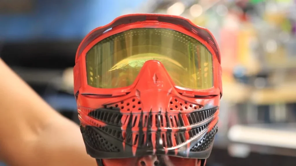 A paintball mask being spray painted in a custom color