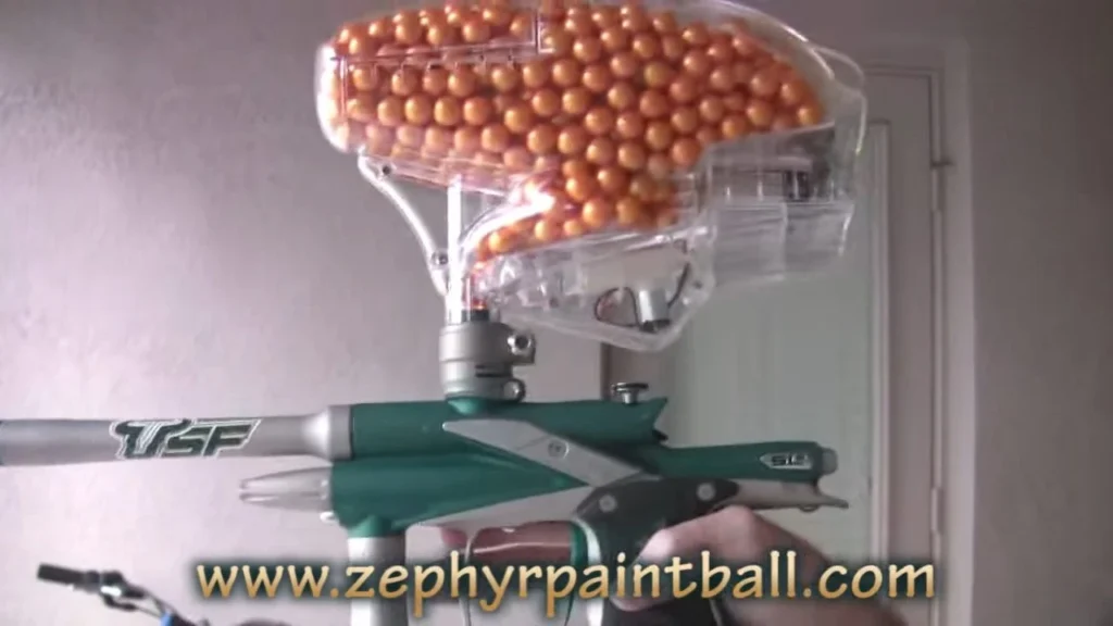 An electronic agitating paintball hopper with its lid open showing the paddle